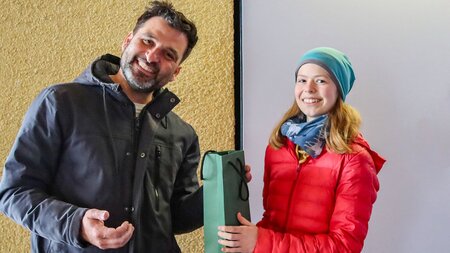 Professor übergibt Geschenk an Schülerin