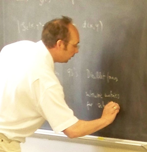 Foto von Profssor Stollmann, wie er etwas an die Tafel schreibt